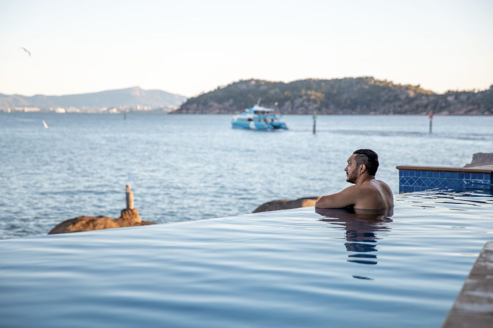 An infinity pool looks out onto the ocean with boats in the water
