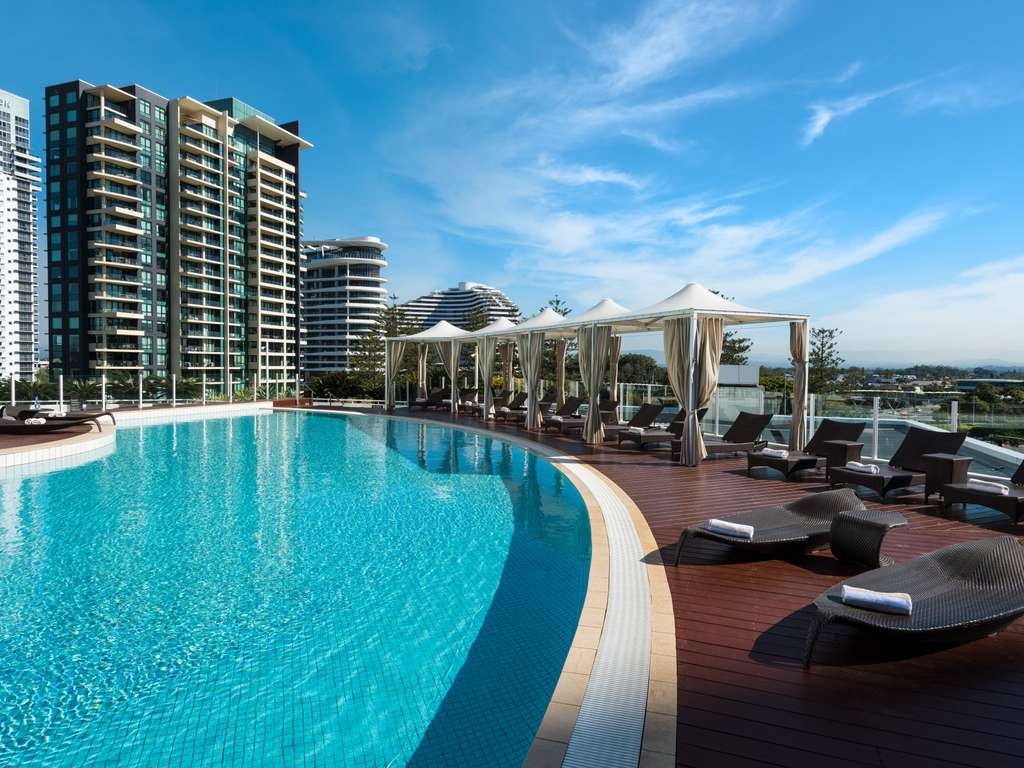 A hotel pool with sun lounges and views of surrounding buildings
