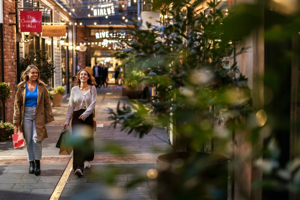 Two people walk along an urban laneway with shopping bags in their hands