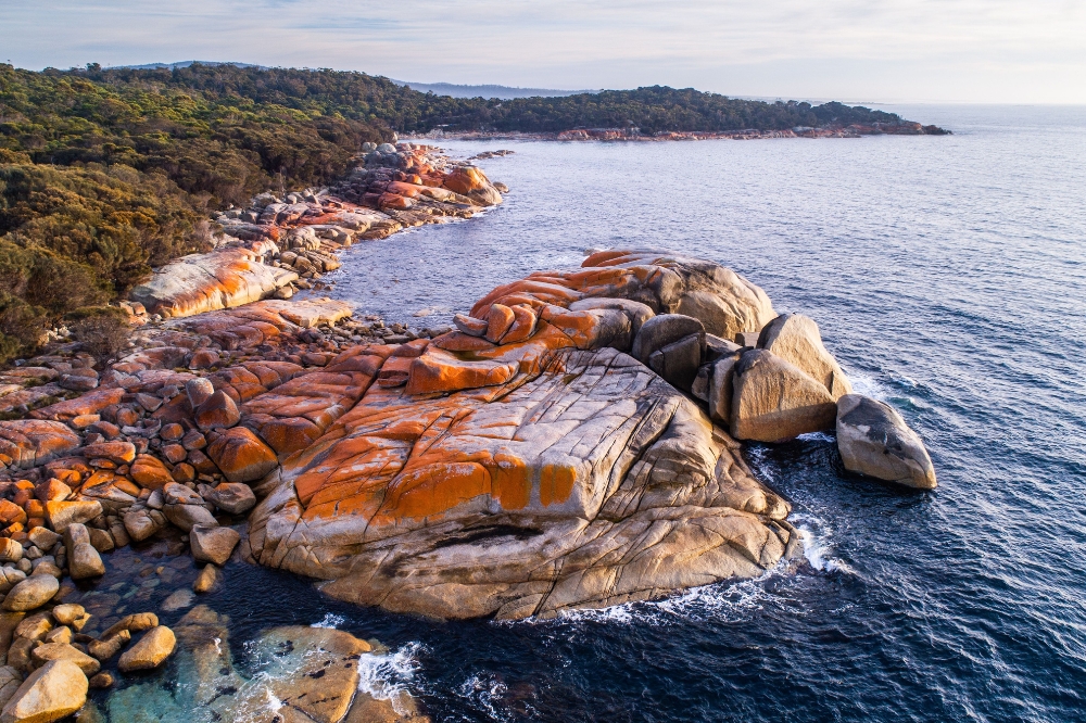 The view of orange rocks lining the ocean shore